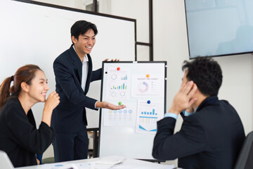 Enthusiastic Presentation and Team Energy. A young man presents budget findings with excitement to his colleagues.
