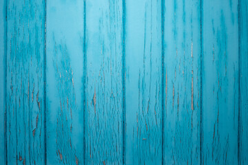 Old wooden blue door with peeling paint, metal handle, rusty bolts, cracked surface. Vintage rustic texture for architecture, renovation, design, decor, historical restoration, construction business,