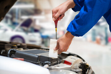 Obraz premium Close up of a car mechanic checking oil level in a mechanical at workshop