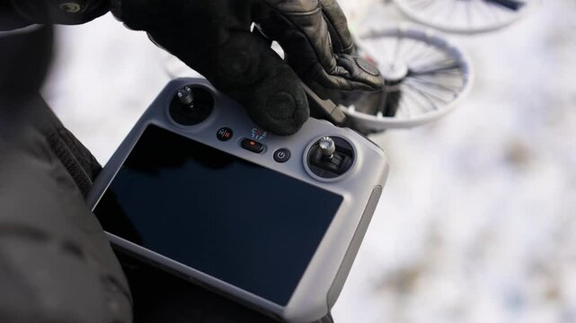 Gloved hands unfolding antennas on drone controller in winter, Czechia