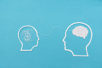 Two white head outlines with Tangled Threads and Puzzle Brain on Blue Background connected by thread, symbolizing communication and mental health