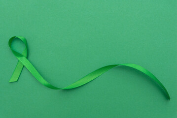 Green awareness ribbon symbolizing mental health on a green background