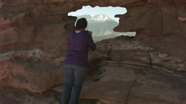 Lady Taking a Picture of Pikes Peak Through Garden of the Gods