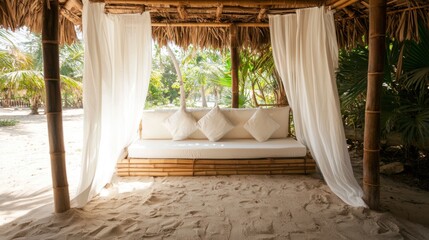 A serene outdoor seating area with a bamboo structure, white cushions, and flowing curtains, surrounded by lush greenery and sandy ground.