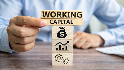 Man holding wooden cubes sees inscription WORKING CAPITAL. Working capital business concept