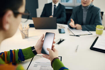 Employee using his smartphone while talking to business people at interview