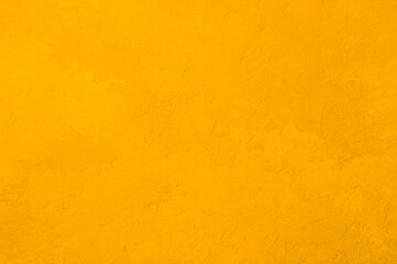 Yellow textured stucco wall with rough plaster surface and warm vibrant color