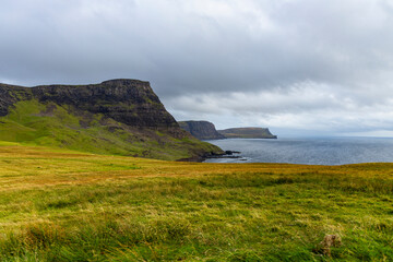 Neist Point at sunset is a breathtaking sight&mdash;its lighthouse stands against dramatic cliffs, with waves crashing below. A rainbow arches over the ocean, painting the rugged Isle of Skye magical light