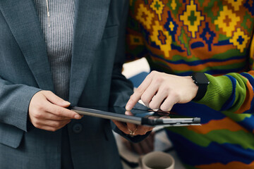Close-up of colleagues using digital tablet during teamwork in office