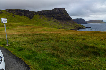 Neist Point at sunset is a breathtaking sight&mdash;its lighthouse stands against dramatic cliffs, with waves crashing below. A rainbow arches over the ocean, painting the rugged Isle of Skye magical light