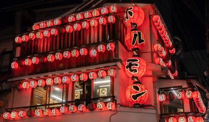 Illuminated Osaka Japanese Yakiniku restaurant at night. Numerous red paper lanterns with Japanese...