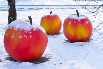 Three large artificial apples in the snow. Winter installation