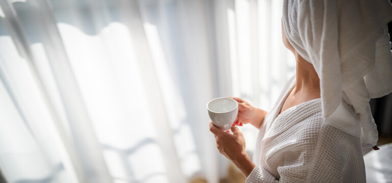 Woman in bathrobe with cup of coffee at home in the morning