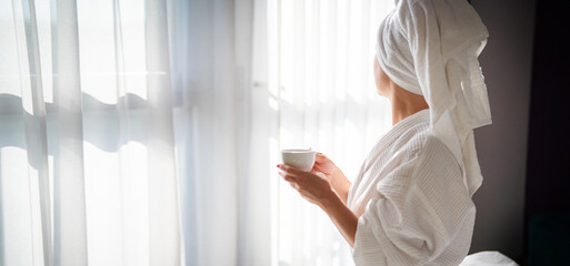 Woman in bathrobe with cup of coffee at home in the morning