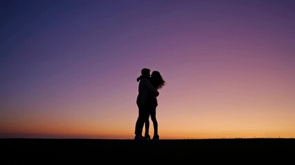 Silhouette of a romantic couple kissing and embracing on a hill against a beautiful gradient sunset sky, symbolizing love, passion, intimacy, connection and relationship goals themes