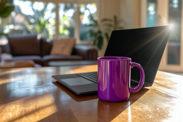 A purple mug next to a laptop on a wooden table with sunlight streaming through windows in a bright, cozy living room.