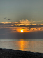 Dramatic sunset over calm ocean with glowing clouds