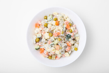 Olivier salad, a classic Russian dish, served in a bowl with a top view on a white background