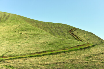 A road and sky running up a grassy green hill. An imaginative photograph.