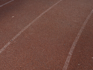 Close-up texture of rubberized running track on stadium with marked lanes.