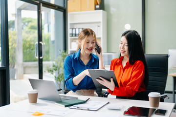 Asian business colleague business presents and explains and using laptop and tablet. Teamwork, financial