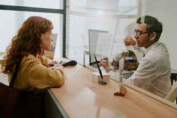 Client discussing financial options with bank consultant in office environment with natural light surrounding, consultant focused on explaining details to female client
