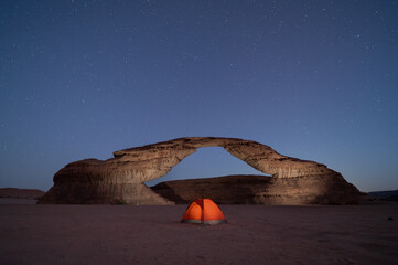 stars motion in rainbow arch night camping tent, with beautiful rock Al ula, Madinah,  Saudi Arabia