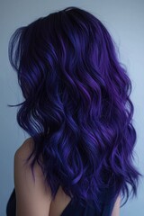 Obraz premium Rear portrait of a woman with voluminous wavy dark purple hair, styled in soft curls and illuminated by cool lighting.