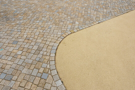 &Uuml;bergang Natursteinpflaster zum Fallschutzbelag an einem Spielplatz