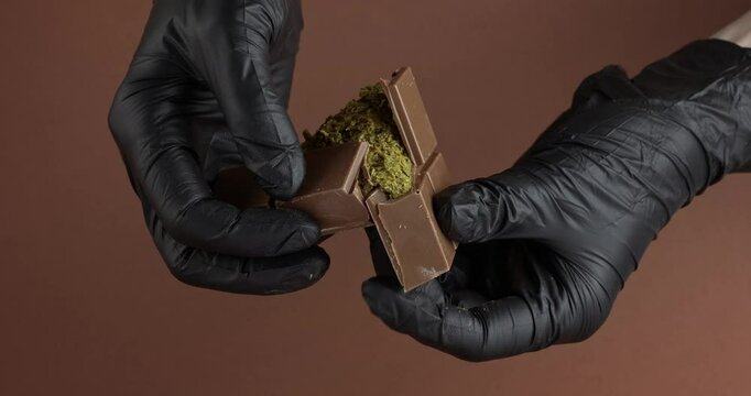Hands in gloves break, cracking Dubai chocolate with pistachio paste and kataifi. Slow motion.