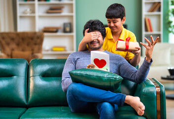 Indian son excitedly gives his father a flower, gift on Father's Day, celebrating together at home