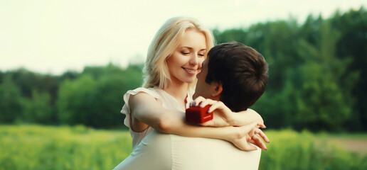 Fototapeta premium Wedding happy lovely young couple, man proposing a ring to his beloved woman outdoors in summer park