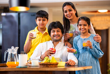 Happy Indian parents and kids share breakfast at the dining table, enjoying quality family time