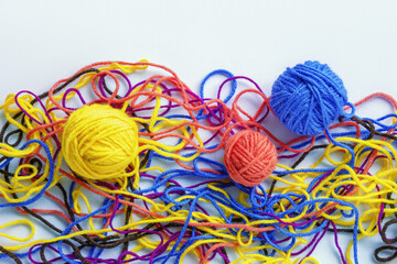 Untangling tangled threads. Multicolored tangled threads and  attempt to wind them into balls. White background, flat lay, copy space