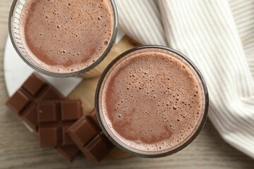 Tasty chocolate milk and bars on wooden table, top view
