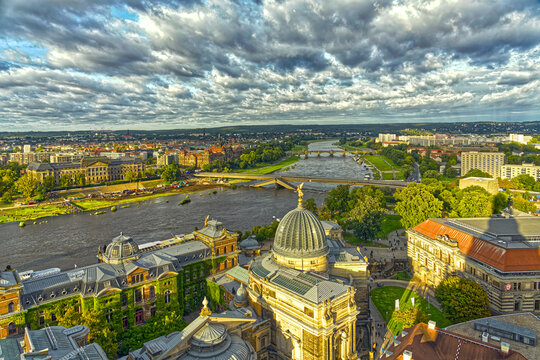 Blick auf die teileingest&uuml;rtzte Carolabr&uuml;cke in Dresden.
Viele Menschen sehen sich beidseitig der Elbe die neue Baustelle mit vielen Baggern an. Das abendliche Sonnenlicht f&auml;rbt die Altstadt gelb.