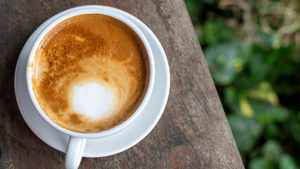 Cup of cappuccino with visible milk foam ring on rustic wooden surface