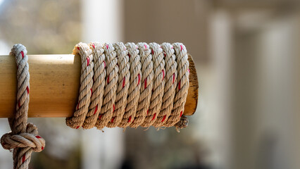 A thick rope wrapped around a bamboo pole in a traditional Thai setting