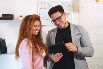 Smiling business colleagues analyzing data on a tablet in a modern office setting