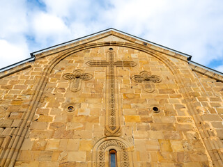 Ananuri Fortress, with big cross on wall of church buildings on blue sky background, historic...