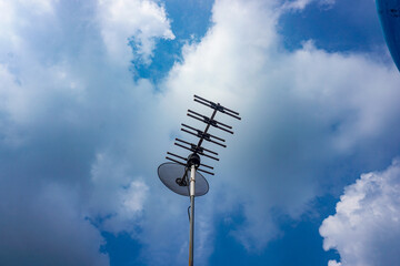 outdoor tv antenna for digital broadcasting with clouds and clear blue sky in the background