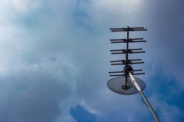 outdoor tv antenna for digital broadcasting with clouds and clear blue sky in the background