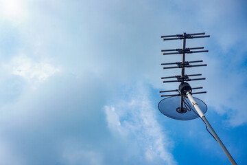 outdoor tv antenna for digital broadcasting with clouds and clear blue sky in the background
