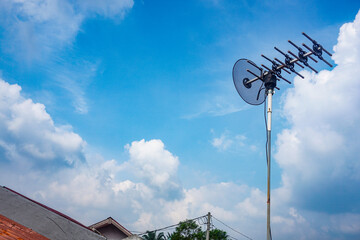 outdoor tv antenna for digital broadcasting with clouds and clear blue sky in the background