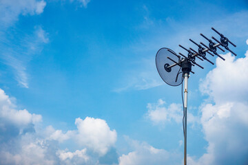 outdoor tv antenna for digital broadcasting with clouds and clear blue sky in the background