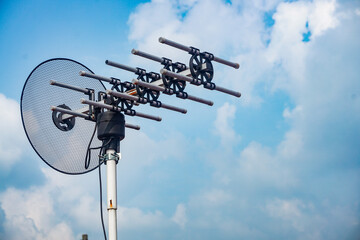 outdoor tv antenna for digital broadcasting with clouds and clear blue sky in the background