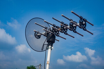 outdoor tv antenna for digital broadcasting with clouds and clear blue sky in the background