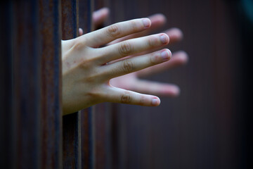 Hands Reaching Through Rusty Bars Symbolizing Hope and Freedom