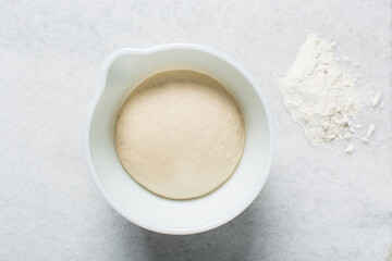 Overhead view of steamed bun dough rising, top view of proofing mantou dough in a bowl, process of making steamed milk buns