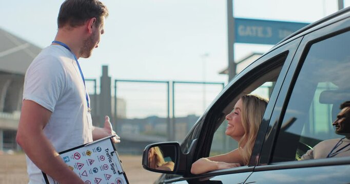 Instructor giving a five to a woman driver sitting in the car while learning to drive on the training ground. Driver courses, exam and people concept.